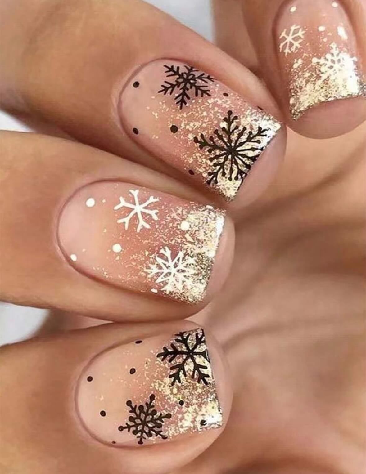 Ongles courts nude avec flocons de neige noirs et paillettes dorées