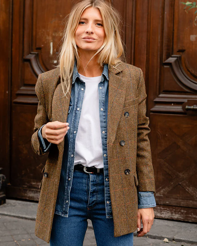 Femme portant un blazer camel sur une chemise en jean et un t-shirt blanc.