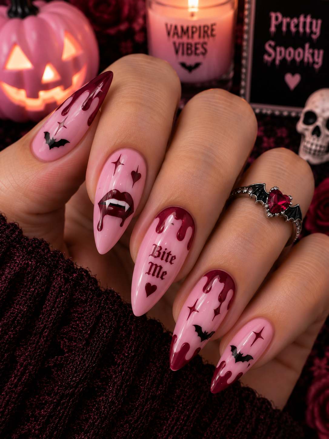 Ongles roses avec motifs vampires et gouttes de sang rouges.