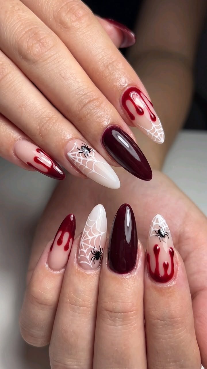 Ongles longs avec motifs toile d'araignée, araignée noire et effet sang rouge.