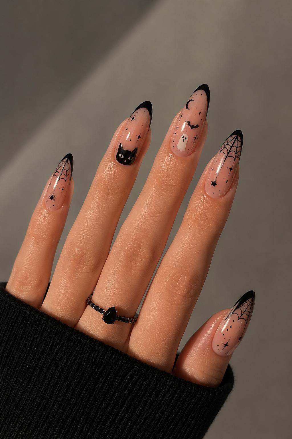 Ongles longs avec motifs Halloween noirs et blancs sur fond nude.